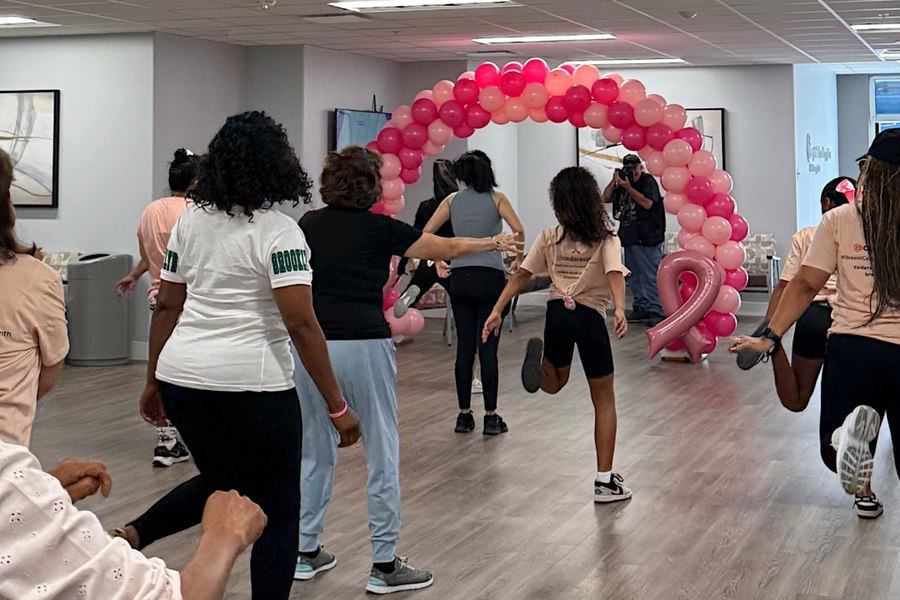 Participants dancing together beneath a pink balloon arch