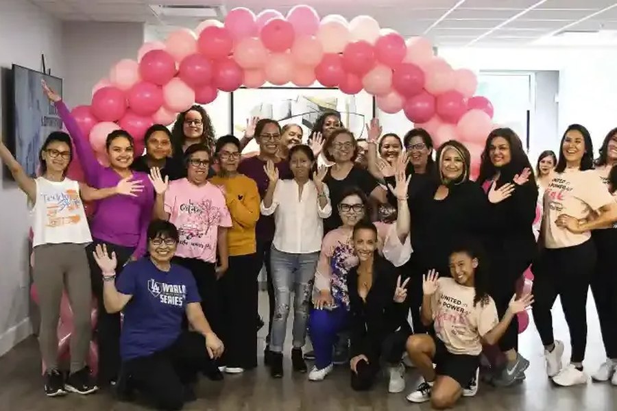 Participants gathered under a pink balloon arch at the end of an event