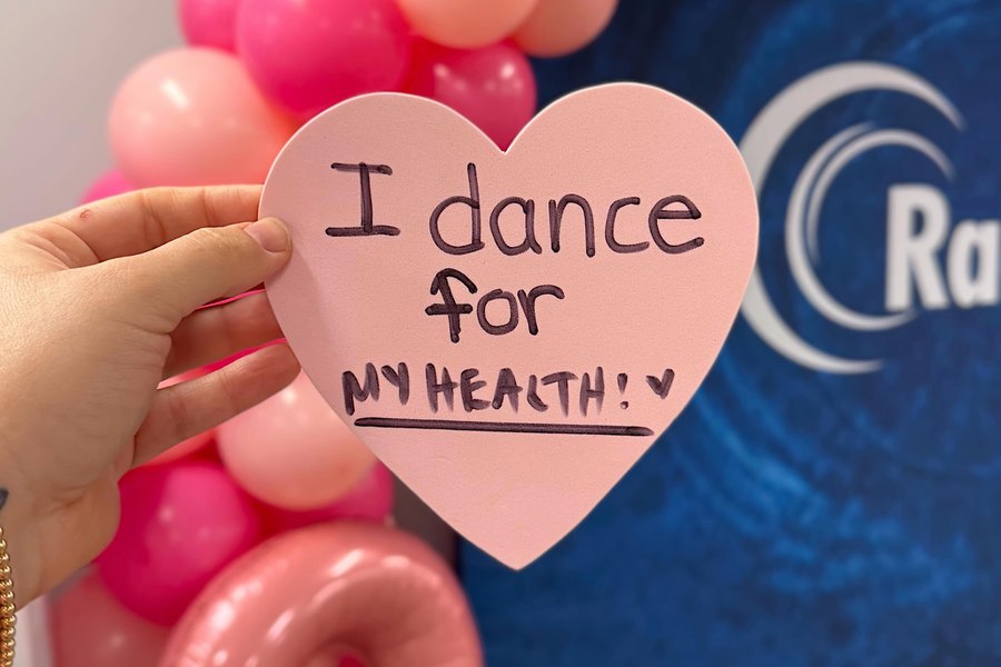 A participant holding a pink paper heart reading “I dance for my health”